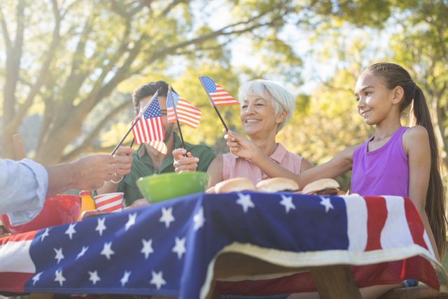 Happy family holding american flags while having meal in the park