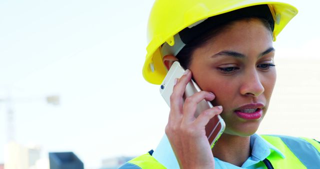 A young African American woman in a hard hat is focused on a phone conversation, with copy space - Download Free Stock Photos Pikwizard.com