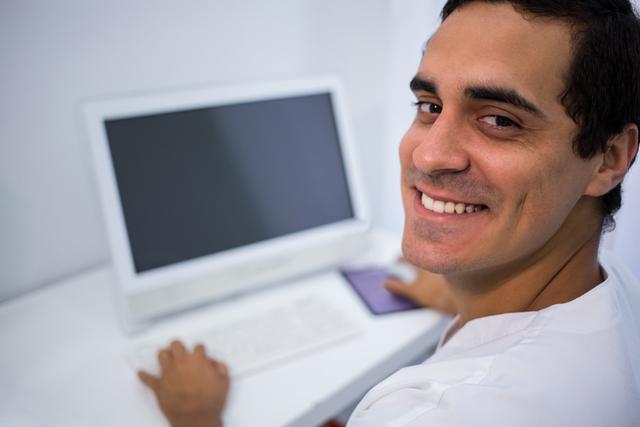 Smiling doctor using desktop pc at clinic - Download Free Stock Photos Pikwizard.com