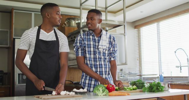 African american senior father and two adult sons standing in kitchen cooking dinner and talking. healthy outdoor family leisure time together.