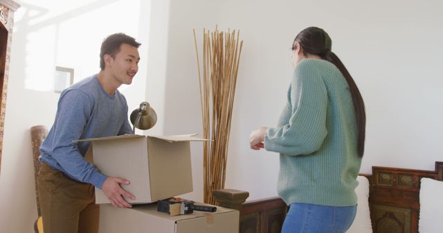 Image of happy diverse couple unpacking boxes after moving in. love, relationship, moving and starting new life together concept.