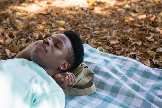 Young man sleeping on a picnic blanket in the park