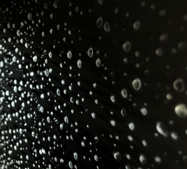 Close up view of multiple water droplets on black background. 