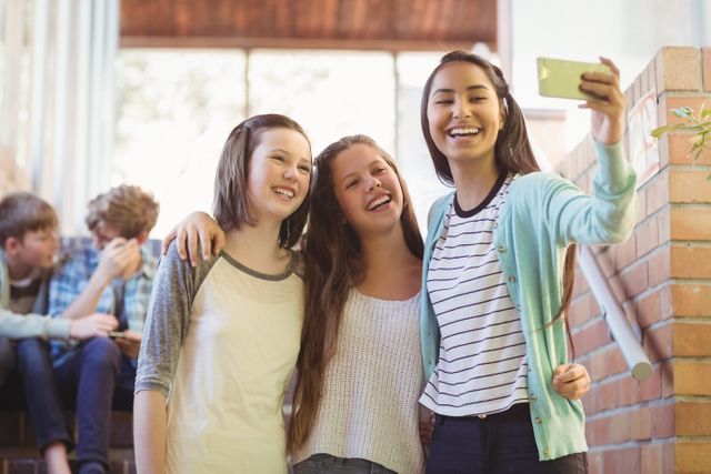 Smiling schoolgirls taking selfie with mobile phone in corridor - Download Free Stock Photos Pikwizard.com