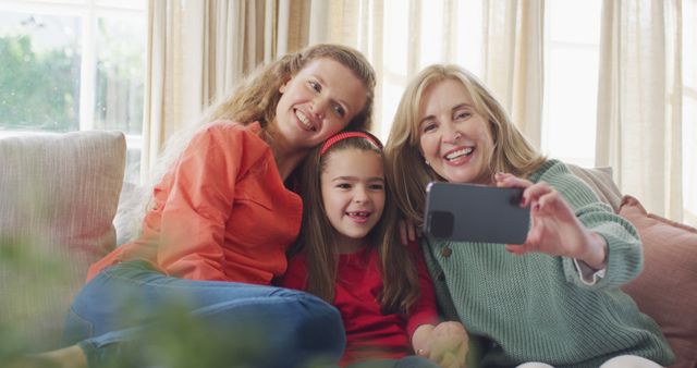 Image of happy caucasian mother and grandmother taking selfie with granddaughter on couch. Family, domestic life and togetherness concept digitally generated image.