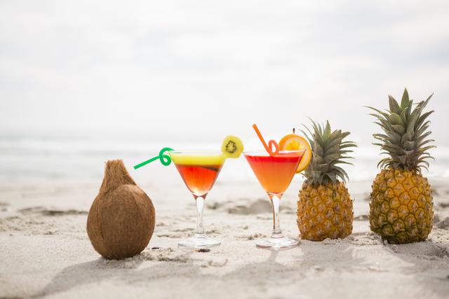 Coconut, pineapples and two glasses of cocktail drink kept on the sand - Download Free Stock Photos Pikwizard.com