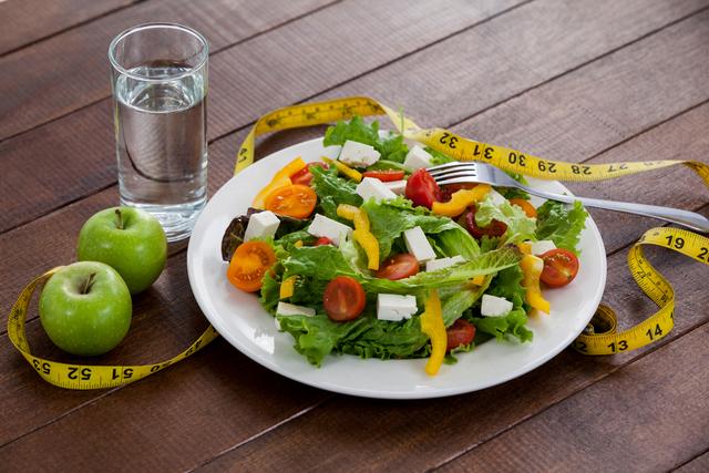 Salad, apple and measuring tape on table - Download Free Stock Photos Pikwizard.com
