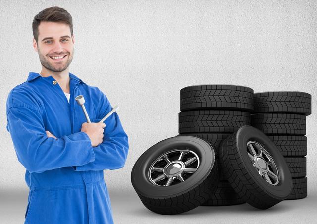 Smiling mechanic holding lug wrench and standing next to tyres - Download Free Stock Photos Pikwizard.com