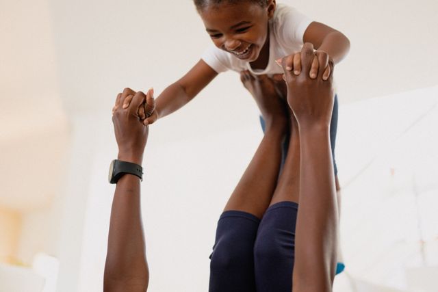 Happy african american daughter playing and exercising with mother at home. family, spending time together at home.