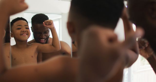 African american father and son flexing their muscles in mirror together - Download Free Stock Photos Pikwizard.com