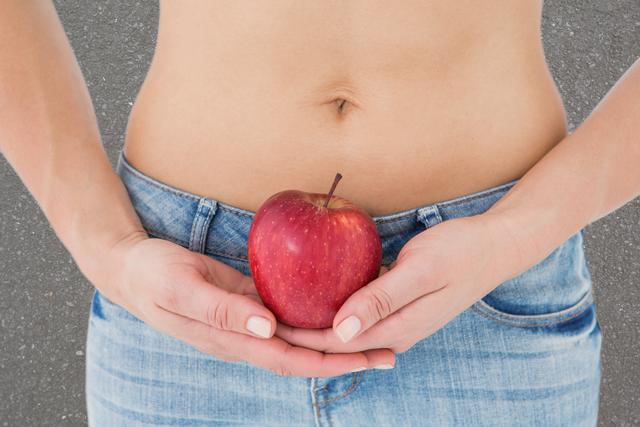Midsection of woman holding apple representing weight loss - Download Free Stock Photos Pikwizard.com