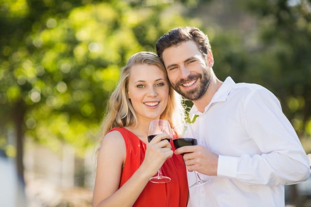 Happy couple holding wine glasses in the park - Download Free Stock Photos Pikwizard.com