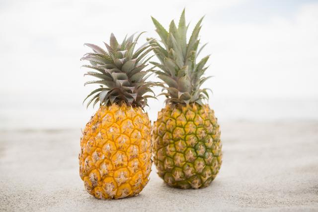 Two pineapples kept on the sand - Download Free Stock Photos Pikwizard.com