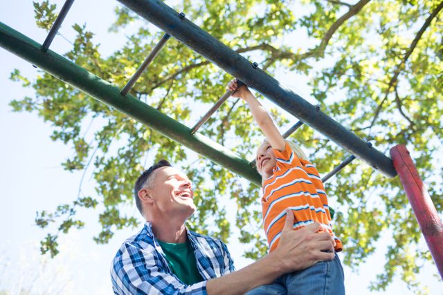 Father holding son playing on jungle gym at playground - Download Free Stock Photos Pikwizard.com