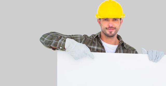 Worker wearing hardhat while pointing at blank bill board - Download Free Stock Photos Pikwizard.com