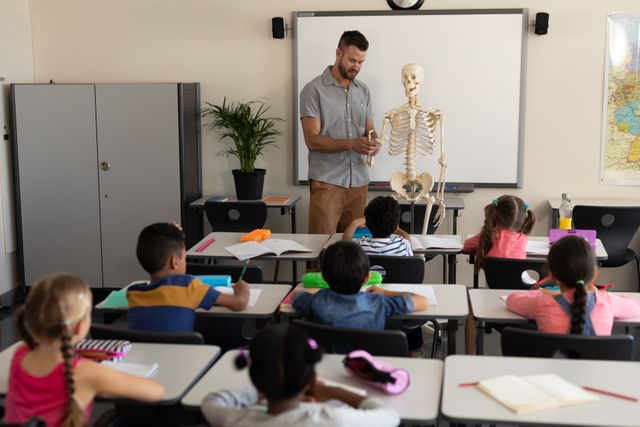 Far sight of male teacher explaining human skeleton model in classroom- Download Free Stock Photos Pikwizard.com