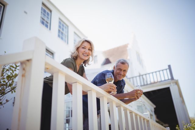 Portrait of mature couple having glasses of wine in balcony - Download Free Stock Photos Pikwizard.com