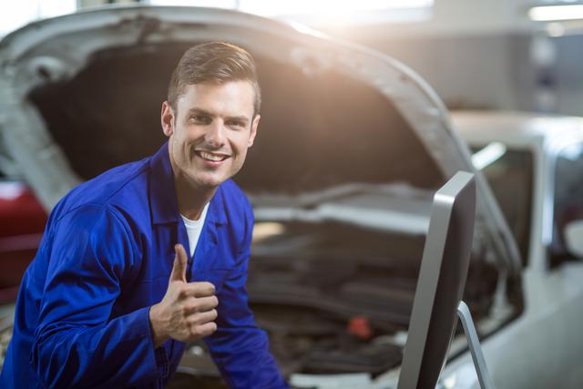 Portrait of mechanic showing thumbs up in repair garage
