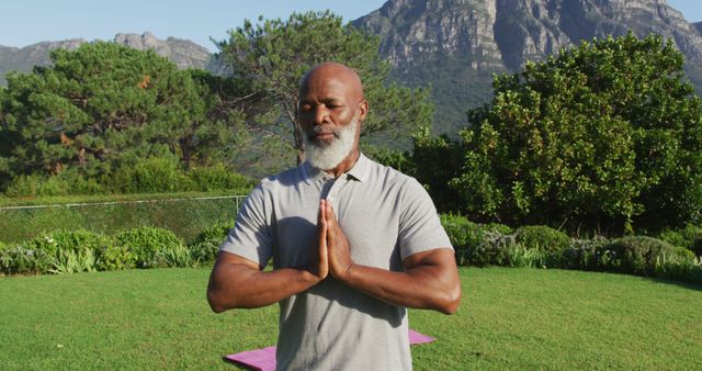 African american senior man practicing yoga and meditating in the garden. retirement sports and active senior lifestyle.