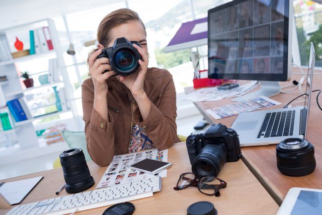 Female executive taking a photograph from digital camera in office