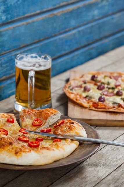 Italian pizza served with glass of beer on wooden plank - Download Free Stock Photos Pikwizard.com
