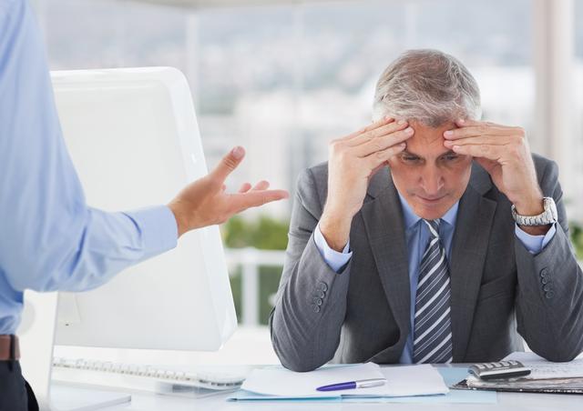 Frustrated businessman sitting with hands on forehead - Download Free Stock Photos Pikwizard.com