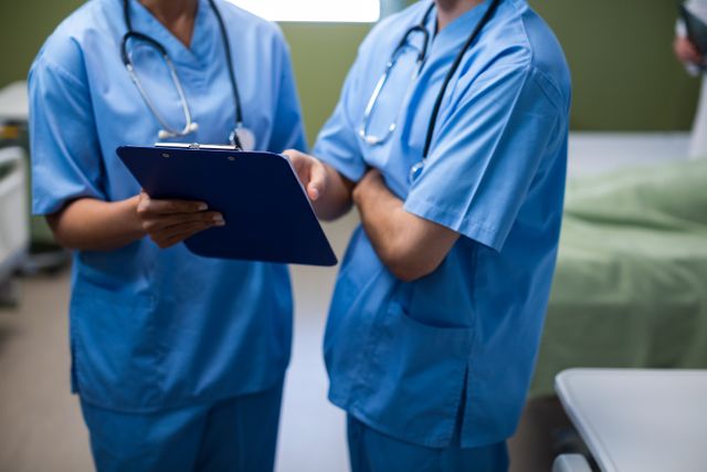 Mid section of male and female nurse having discussion over clipboard in ward - Download Free Stock Photos Pikwizard.com