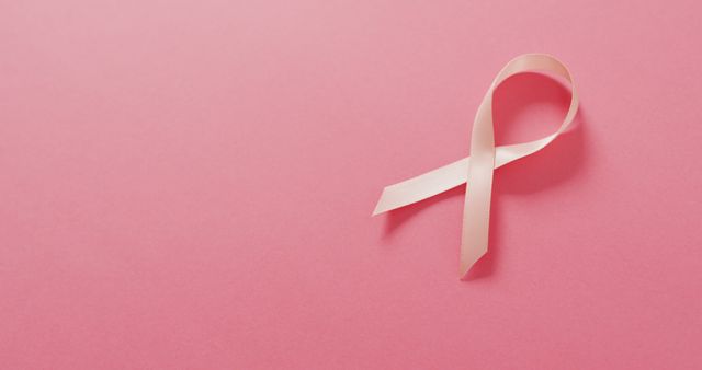 Image of pink breast cancer ribbon on pale pink background. medical awareness support campaign symbol for breast cancer.