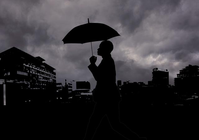 Silhouette of man holding an umbrella against cityscape - Download Free Stock Photos Pikwizard.com