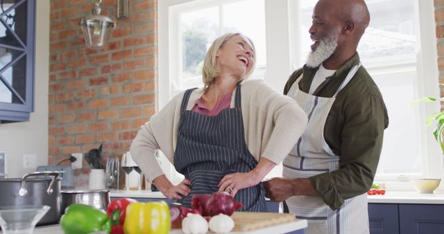 African american senior man tying apron to his wife in the kitchen at home. retirement senior couple lifestyle living concept