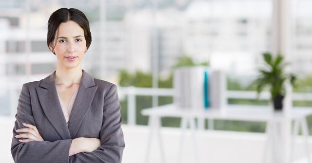 Digital composition of a confident businesswoman standing with arms crossed in office