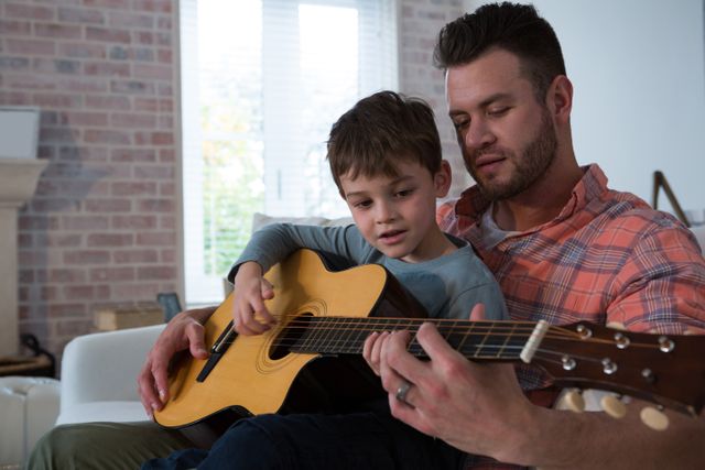 Father assisting his son in playing guitar - Download Free Stock Photos Pikwizard.com