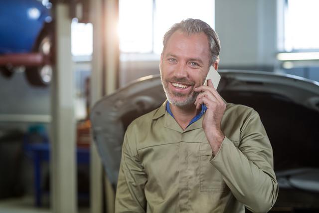 Portrait of smiling mechanic talking on a mobile phone in repair shop