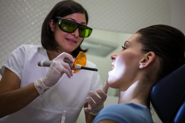 Dentist examining patients teeth with dental curing light - Download Free Stock Photos Pikwizard.com