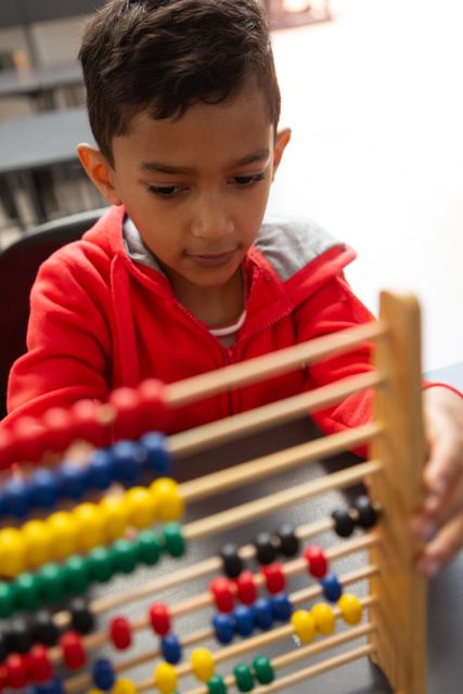 High angle view of cute mixed-race schoolboy learning math with abacus at desk in a classroom at elementary school