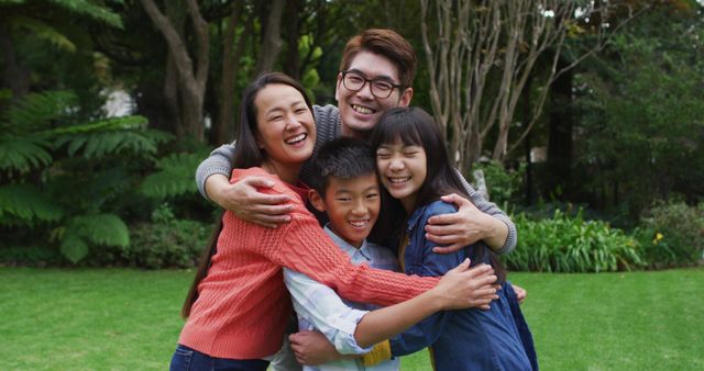 Smiling asian parents hugging happy son and daughter in garden - Download Free Stock Photos Pikwizard.com