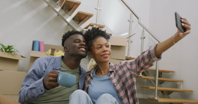 Image of happy african american couple taking selfie after moving into new house. love, relationship, and starting new life together.