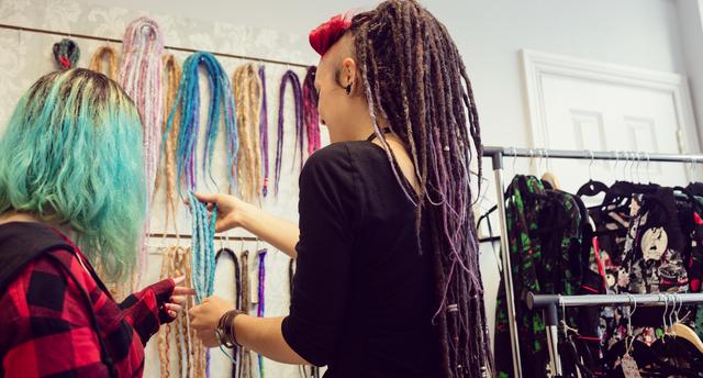 Female shop owner showing dreadlocks to a customer - Download Free Stock Photos Pikwizard.com