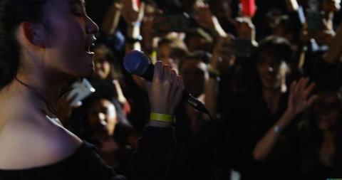 A young female singer enthralls a diverse audience with her lively ...