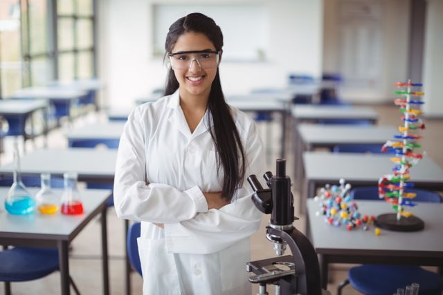Portrait of schoolgirl in lab coat standing with arms crossed in laboratory - Download Free Stock Photos Pikwizard.com