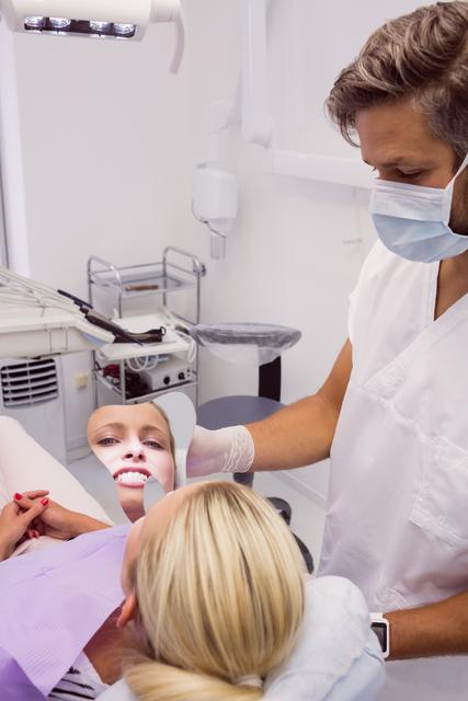 Dentist holding a mirror near patients face - Download Free Stock Photos Pikwizard.com
