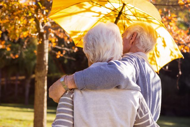 Senior couple embracing under an umbrella - Download Free Stock Photos Pikwizard.com