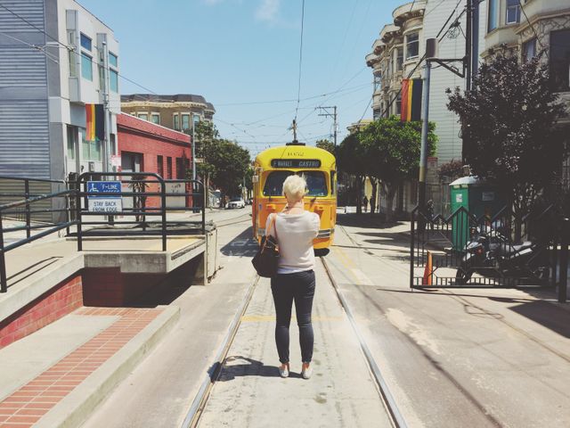 Rear view of a woman standing on the tramway track. transportation concept