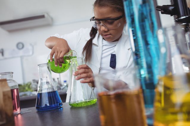 Elementary student pouring green chemical in flask at laboratory - Download Free Stock Photos Pikwizard.com