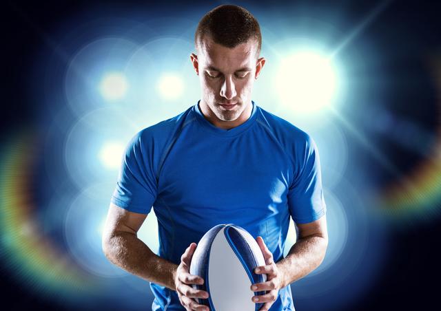 Determined rugby player holding ball against illuminated background