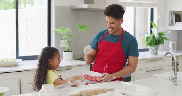 Happy biracial father and daughter baking together in kitchen. domestic lifestyle, spending free time at home.