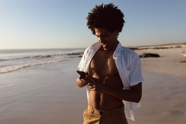 Young man using mobile phone on the beach