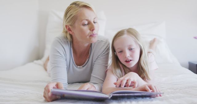 Happy Caucasian Mother And Daughter Lying On Bed Reading Story Book ...