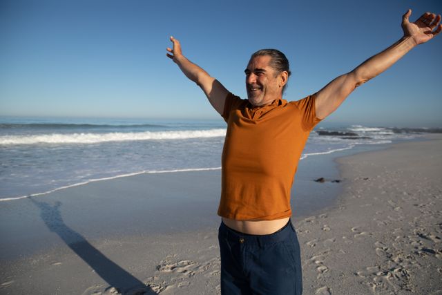 Senior man standing with his arms wide open on the beach - Download Free Stock Photos Pikwizard.com