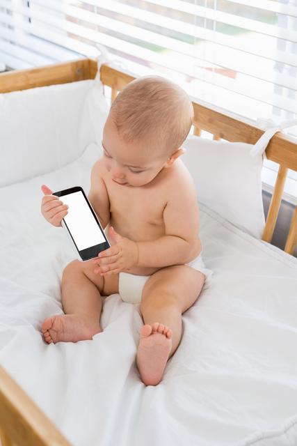 Baby boy playing with mobile phone on a cradle - Download Free Stock Photos Pikwizard.com